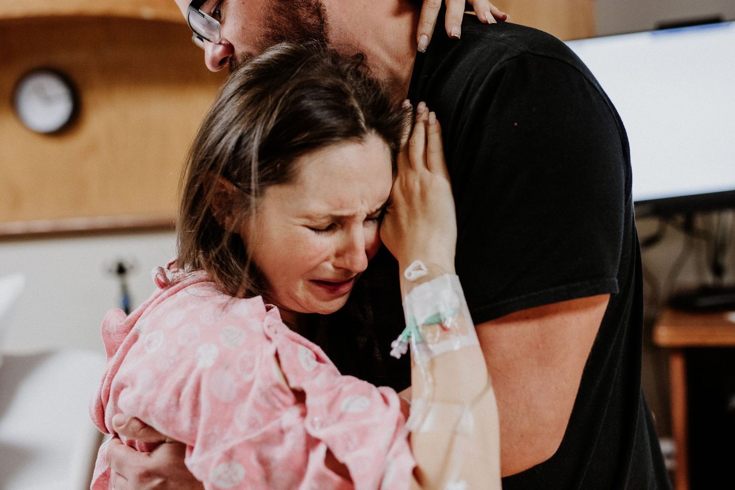 Emotional woman crying and embracing partner during labor in a hospital delivery room.