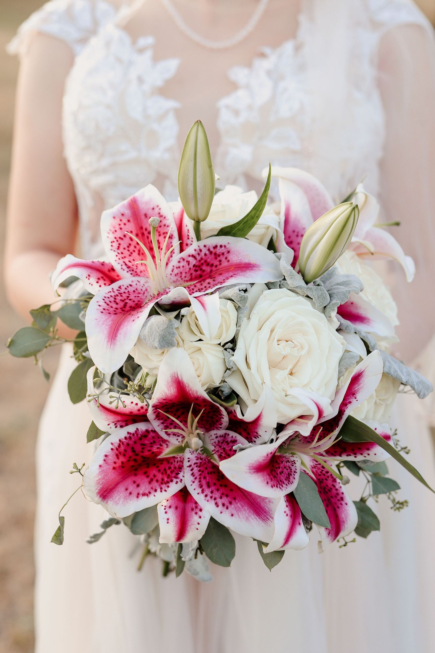 Bride holding a wedding bouquet of pink stargazer lilies, white roses, and eucalyptus greenery.