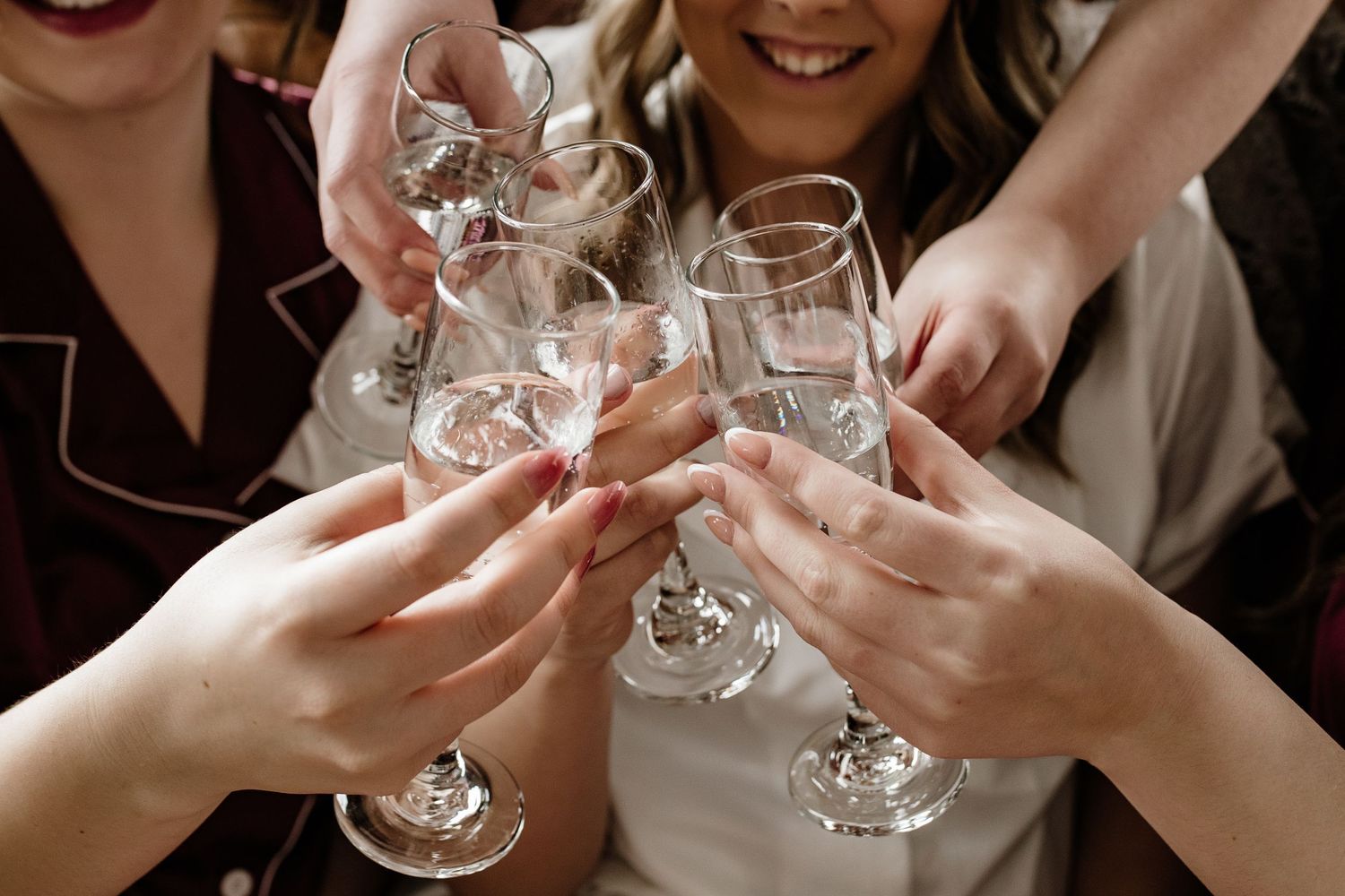 Group of women in pajamas toasting with champagne glasses at a bachelorette party celebration.