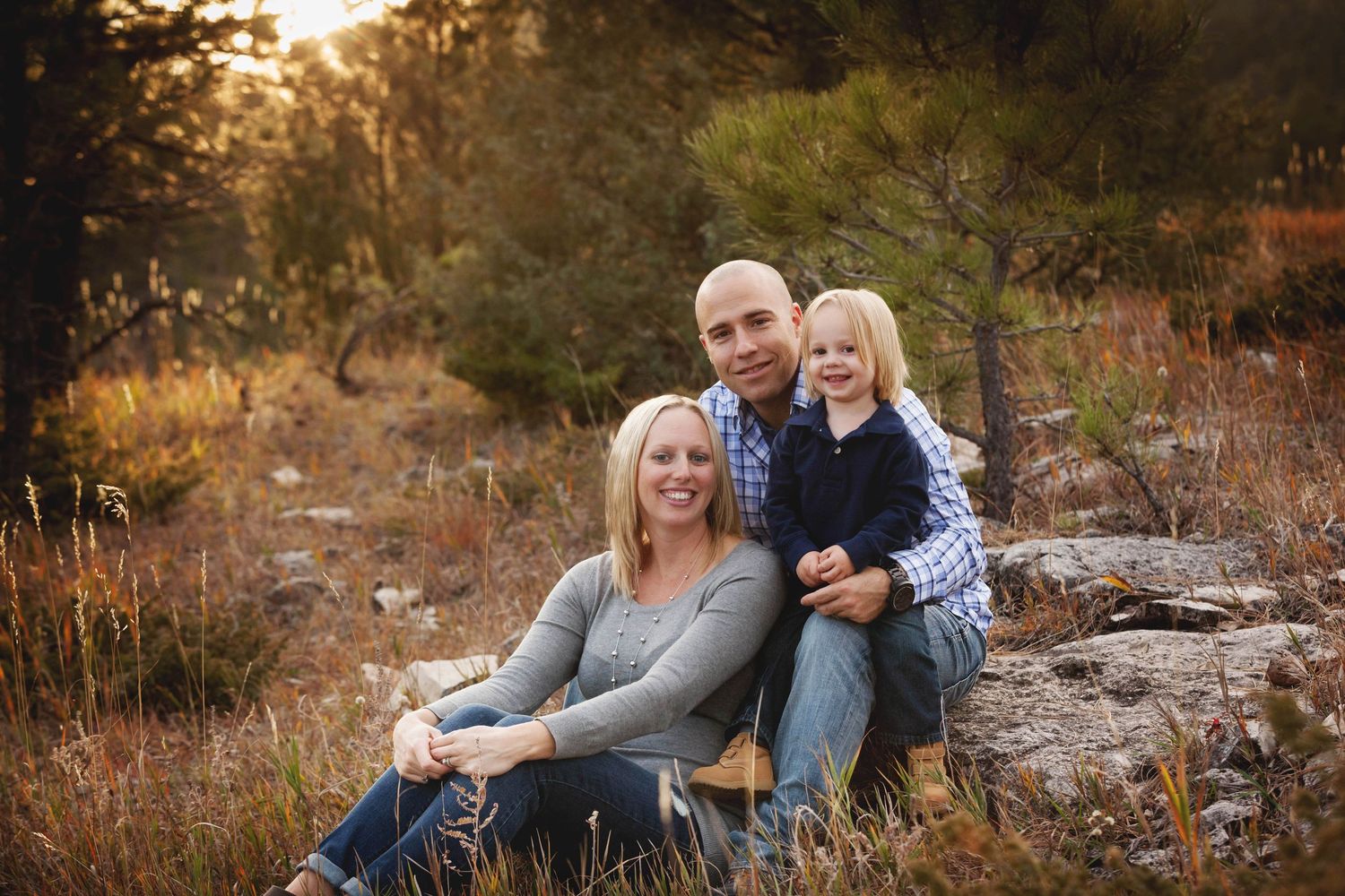Couple sits together on rocks during golden hour autumn photoshoot in nature.