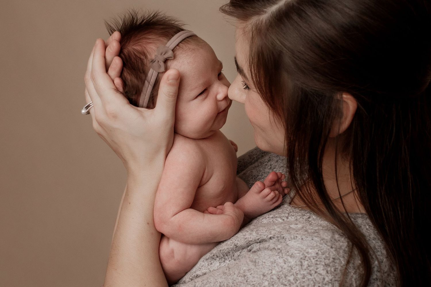 A tender moment between parent and newborn captured in soft warm lighting.