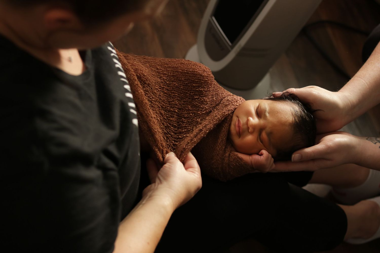 Two hands delicately comb through long brown hair with a textured towel after a shower or haircare treatment.