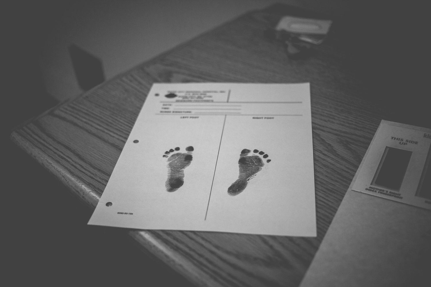 Black and white photo of a newborn baby's ink footprints on a hospital birth record document.