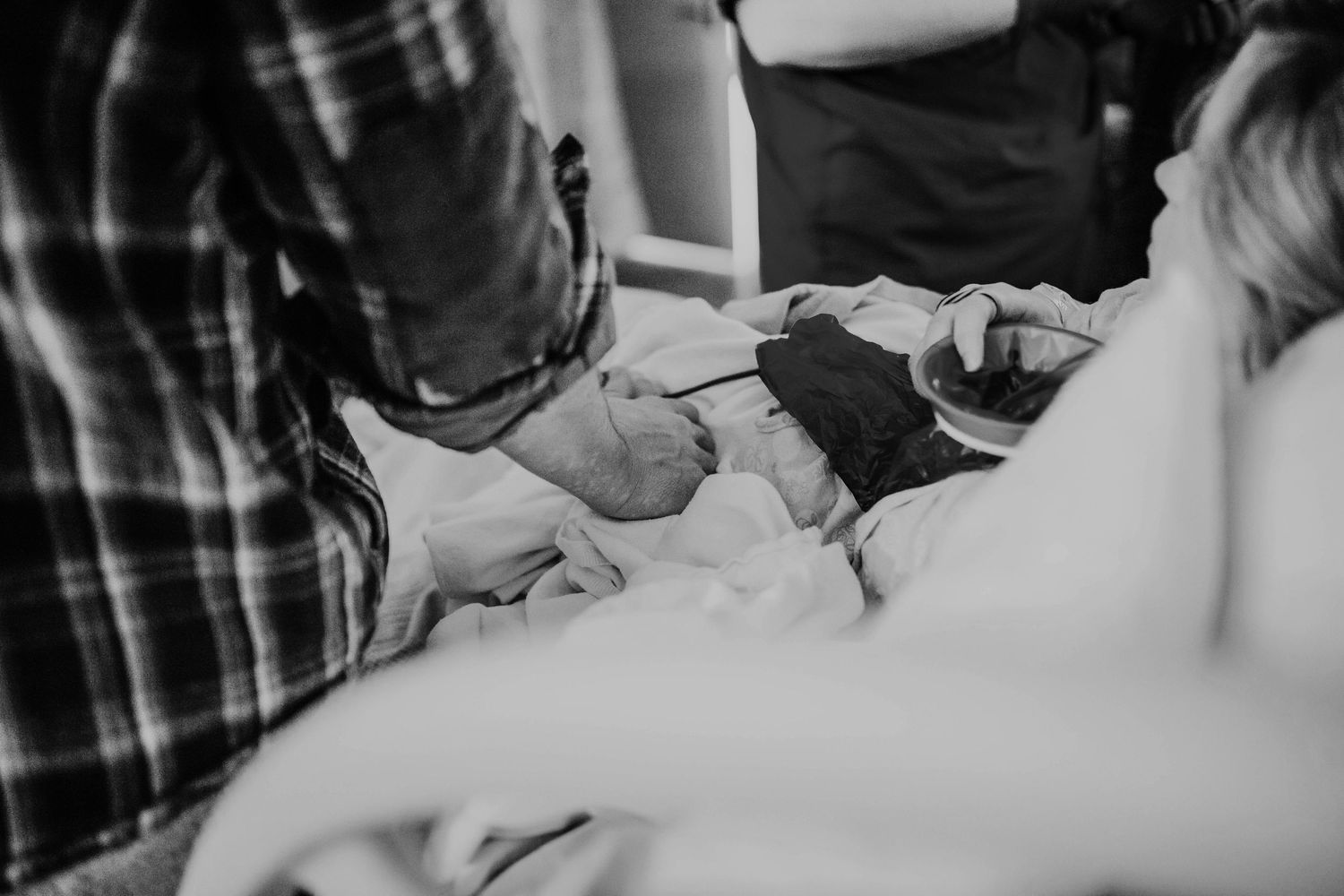 New parents gazing lovingly at their newborn baby wrapped in blankets after birth.