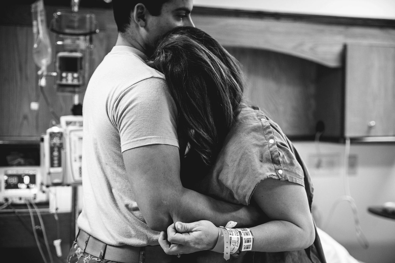 Couple shares emotional embrace in hospital labor and delivery room.