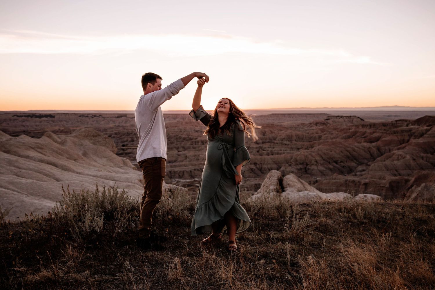 Couple dancing at sunset in the Badlands, woman in green maxi dress, romantic outdoor shoot.