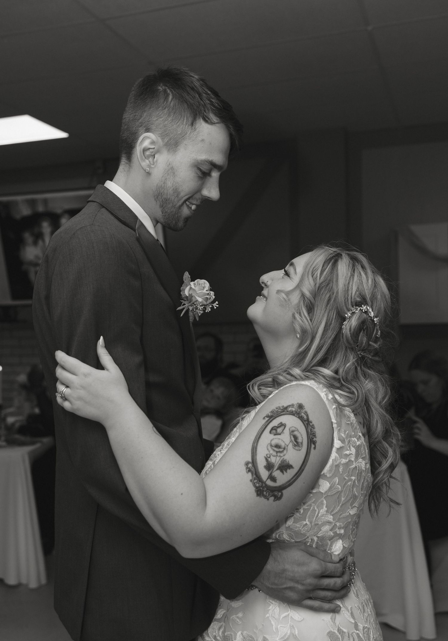 Black and white photo of a bride and groom sharing their first dance at a wedding reception.