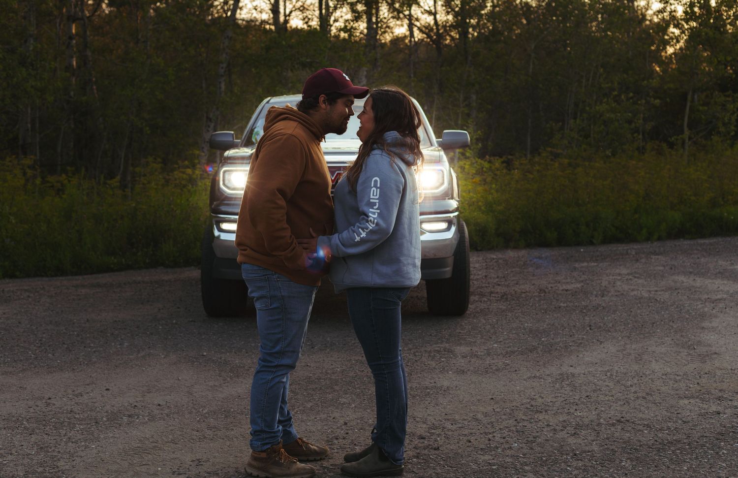 Romantic couple dancing face to face in truck headlights at dusk.