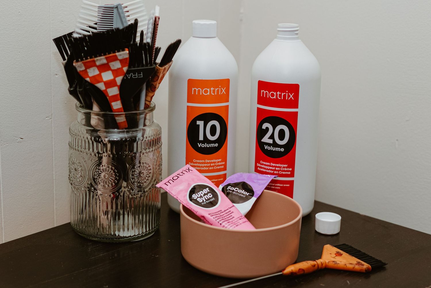 Matrix 10 and 20 Volume developer bottles with hair coloring brushes, mixing bowl, and color swatches on a dark surface.