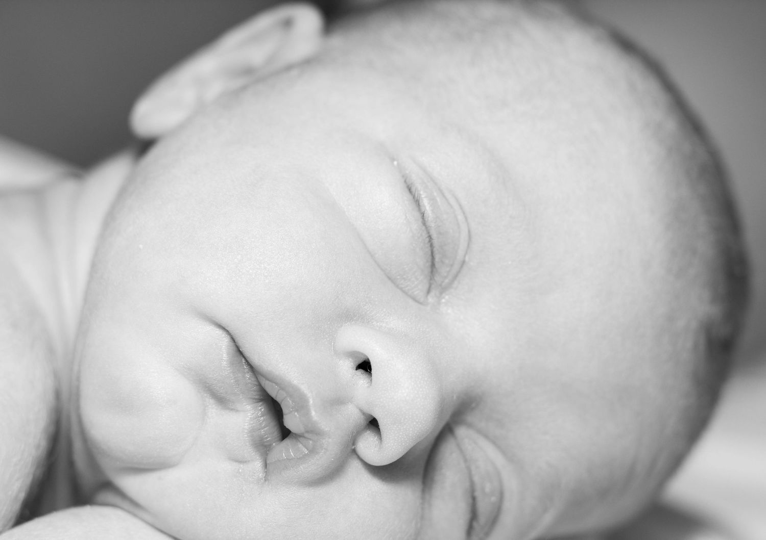Extreme close-up black and white portrait of a sleeping newborn baby's peaceful face.