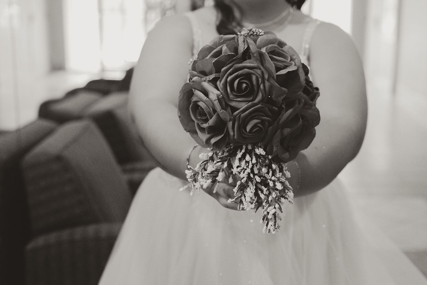 A flower girl in a white dress holds a bouquet of roses at a wedding ceremony.