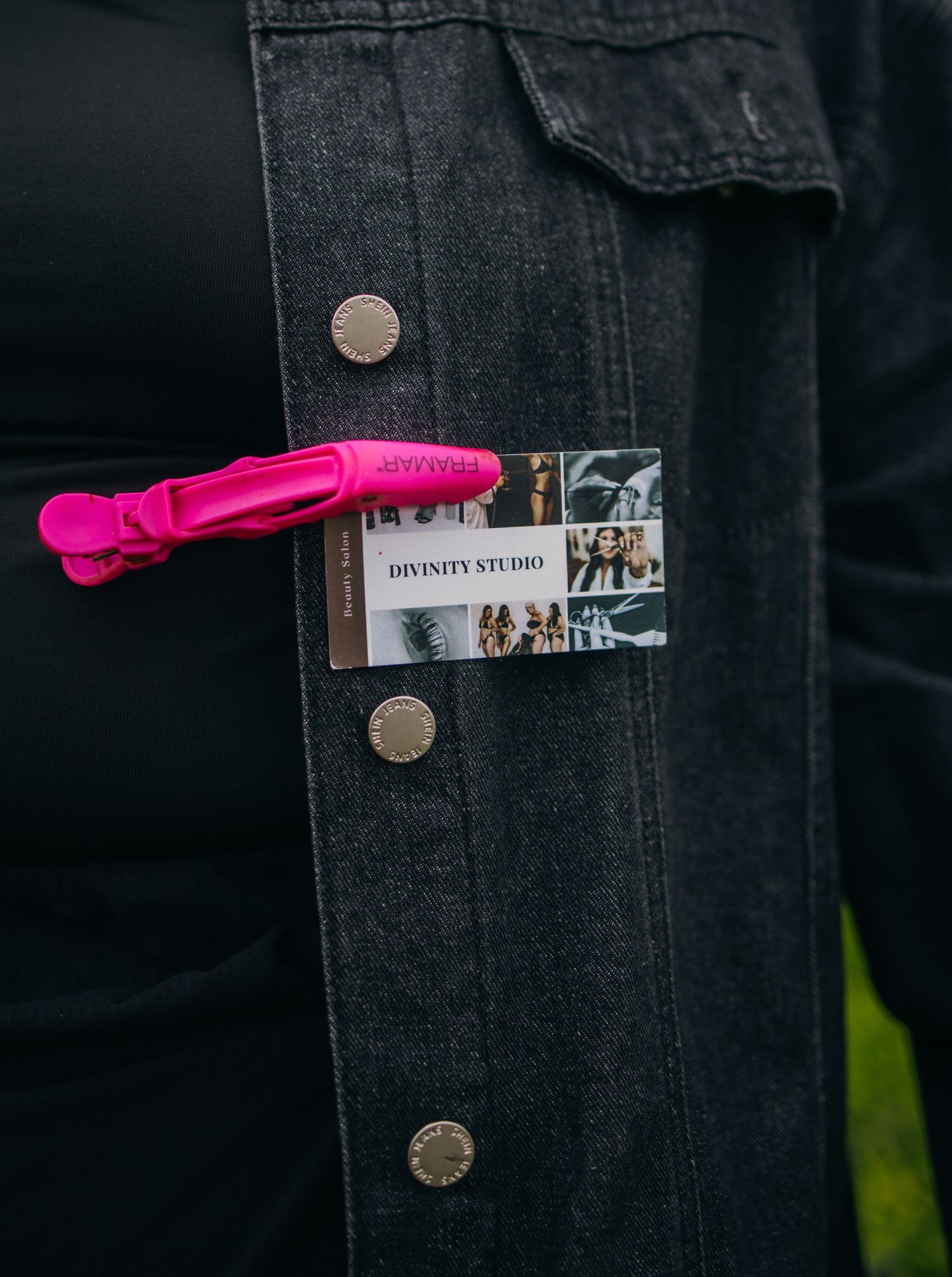 Black denim jacket with Divinity Studio business card and pink hair clip tucked in breast pocket.