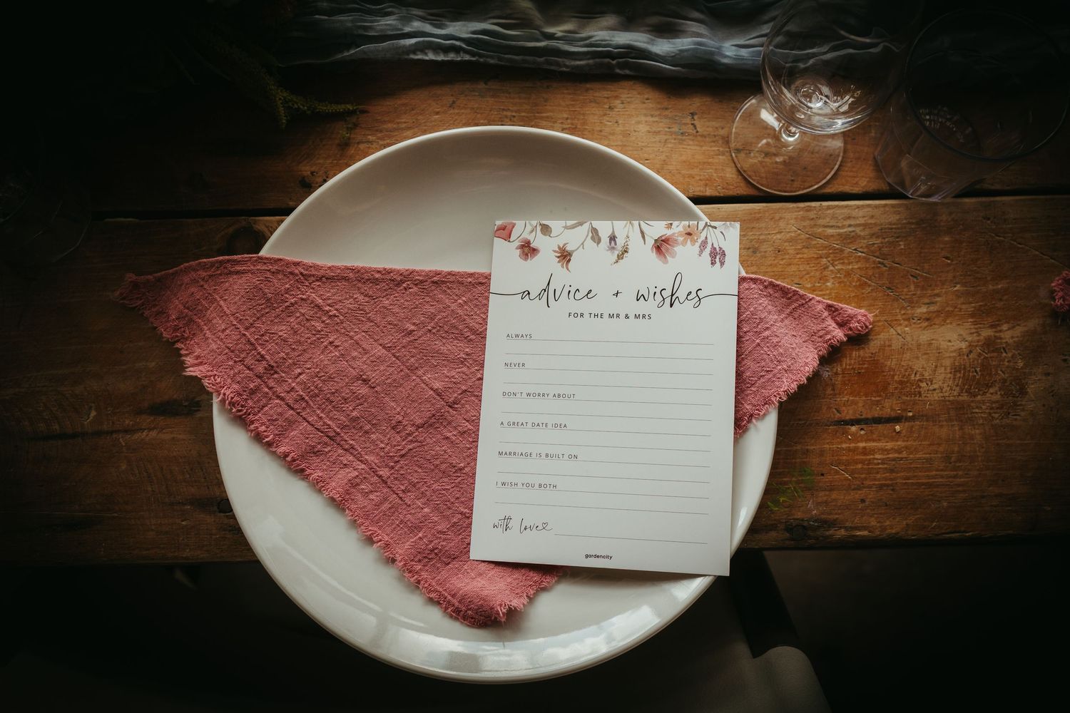 Rustic wedding table setting with advice and wishes card on white plate with dusty rose linen napkin.