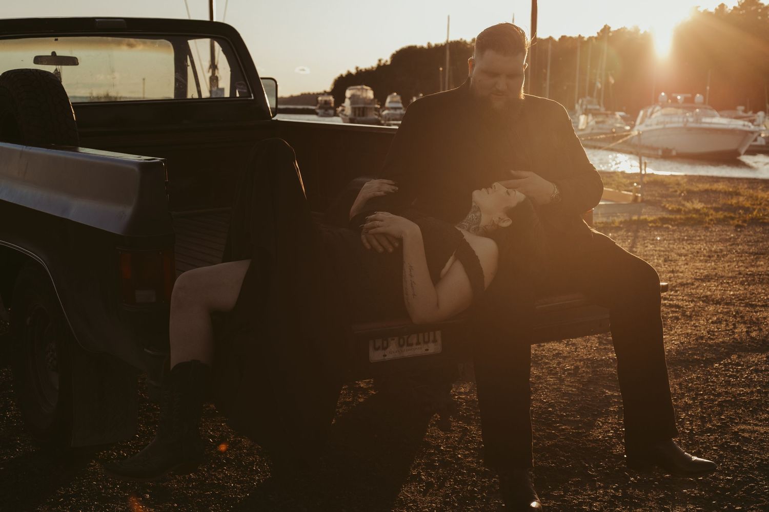 Couple embracing on the tailgate of a vintage truck during a stunning sunset.