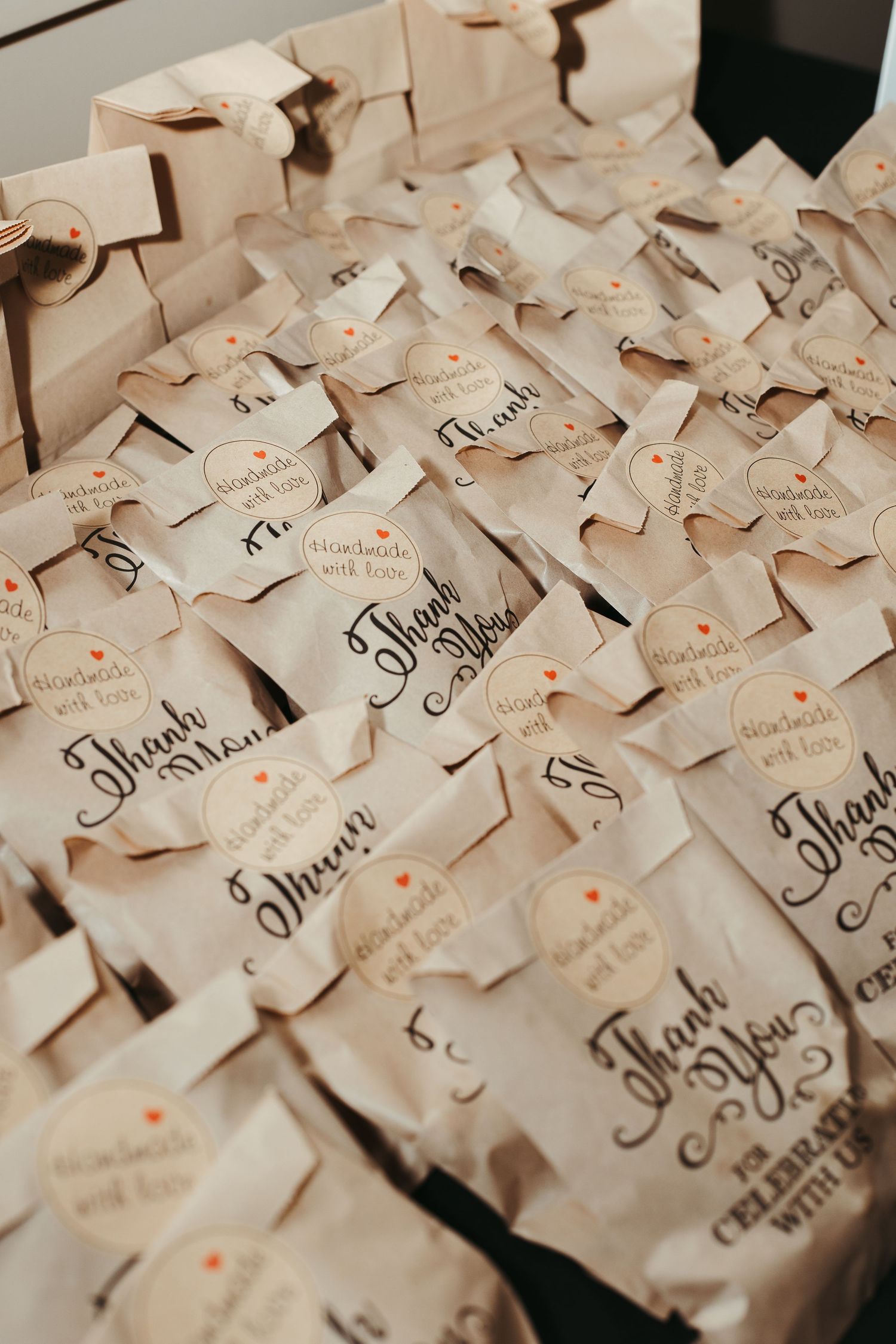 Wedding favor bags labeled Thank You with handmade with love tags arranged on a display table.