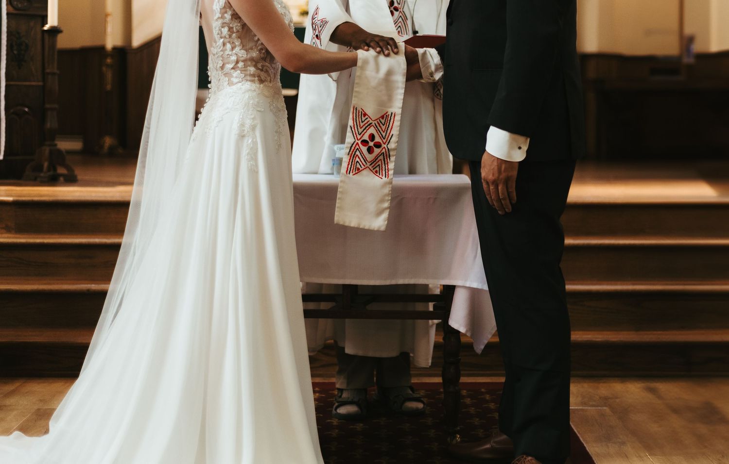 Bride and groom exchanging vows before an officiant at a church wedding ceremony altar.