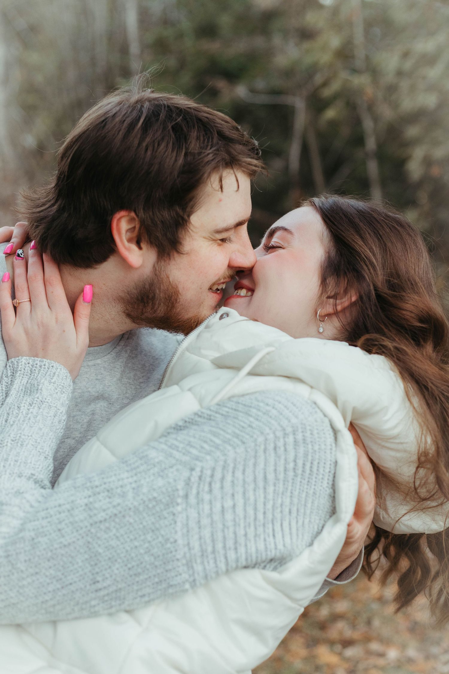 Happy couple shares a tender nose-to-nose moment, smiling and embracing in an outdoor setting.