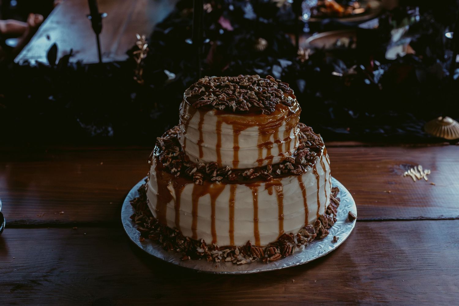 Two-tier caramel drip cake with chocolate decorations on a rustic wooden table.