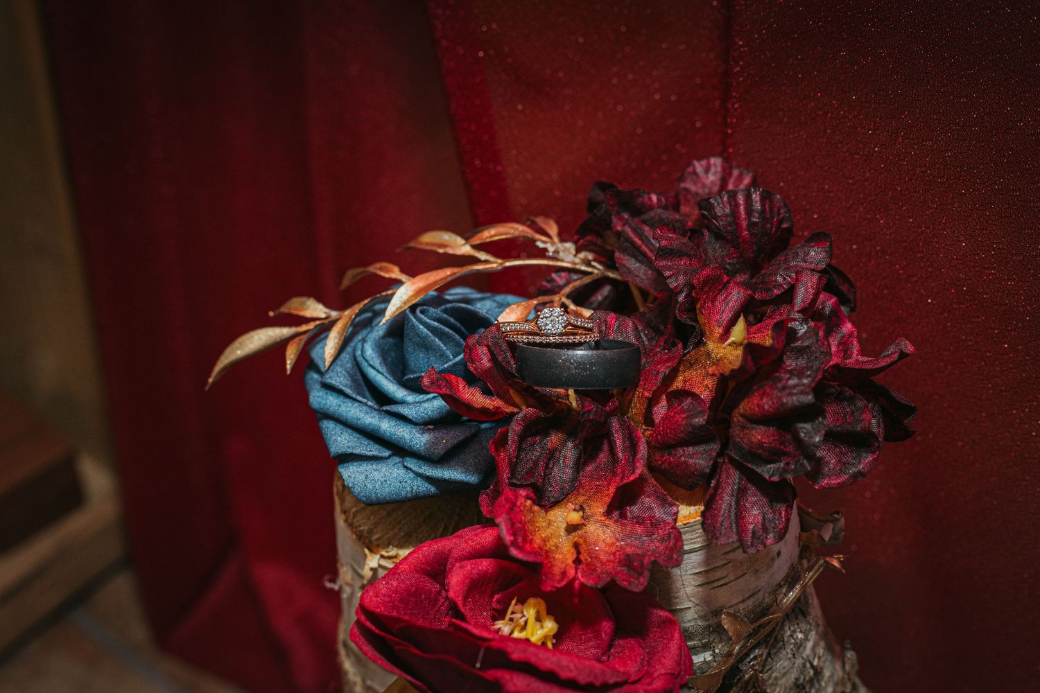 Decorative floral arrangement with blue and burgundy fabric roses and a small ornate bowl centerpiece.