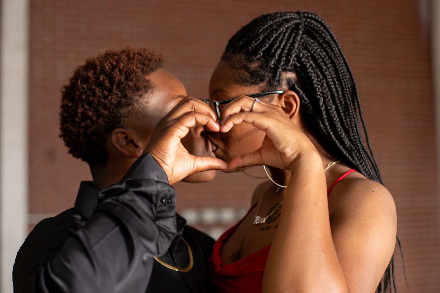 Couple forming a heart shape with their hands close together in a romantic gesture.