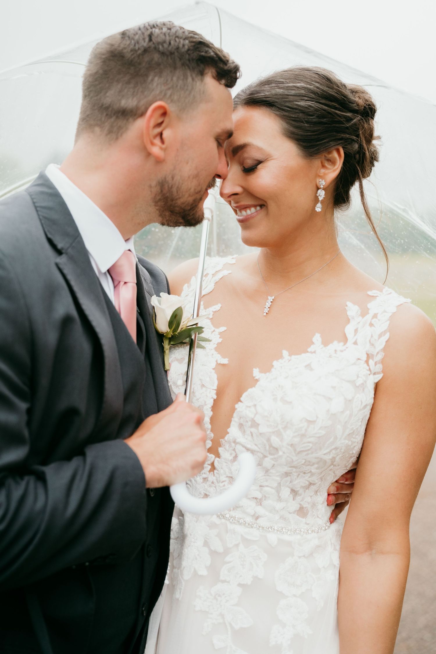 Intimate moment between newlyweds under clear umbrella in Nashville TN