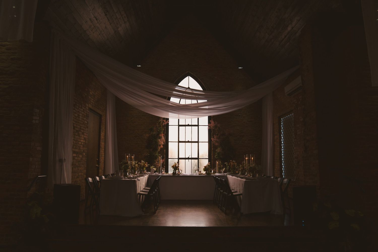 An atmospheric shot of a dimly lit chapel interior with draped fabric and window light.