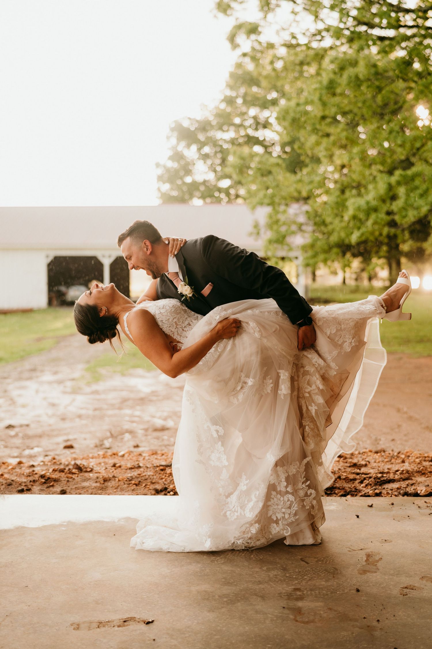 Romantic wedding photo showing a couple dancing in a dip pose, with lace wedding dress flowing on a stone patio at sunset.