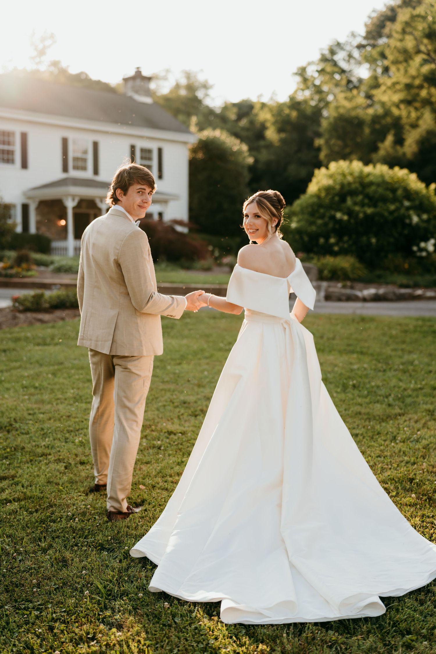 A romantic outdoor wedding scene with a couple in formal attire on a sunlit lawn.