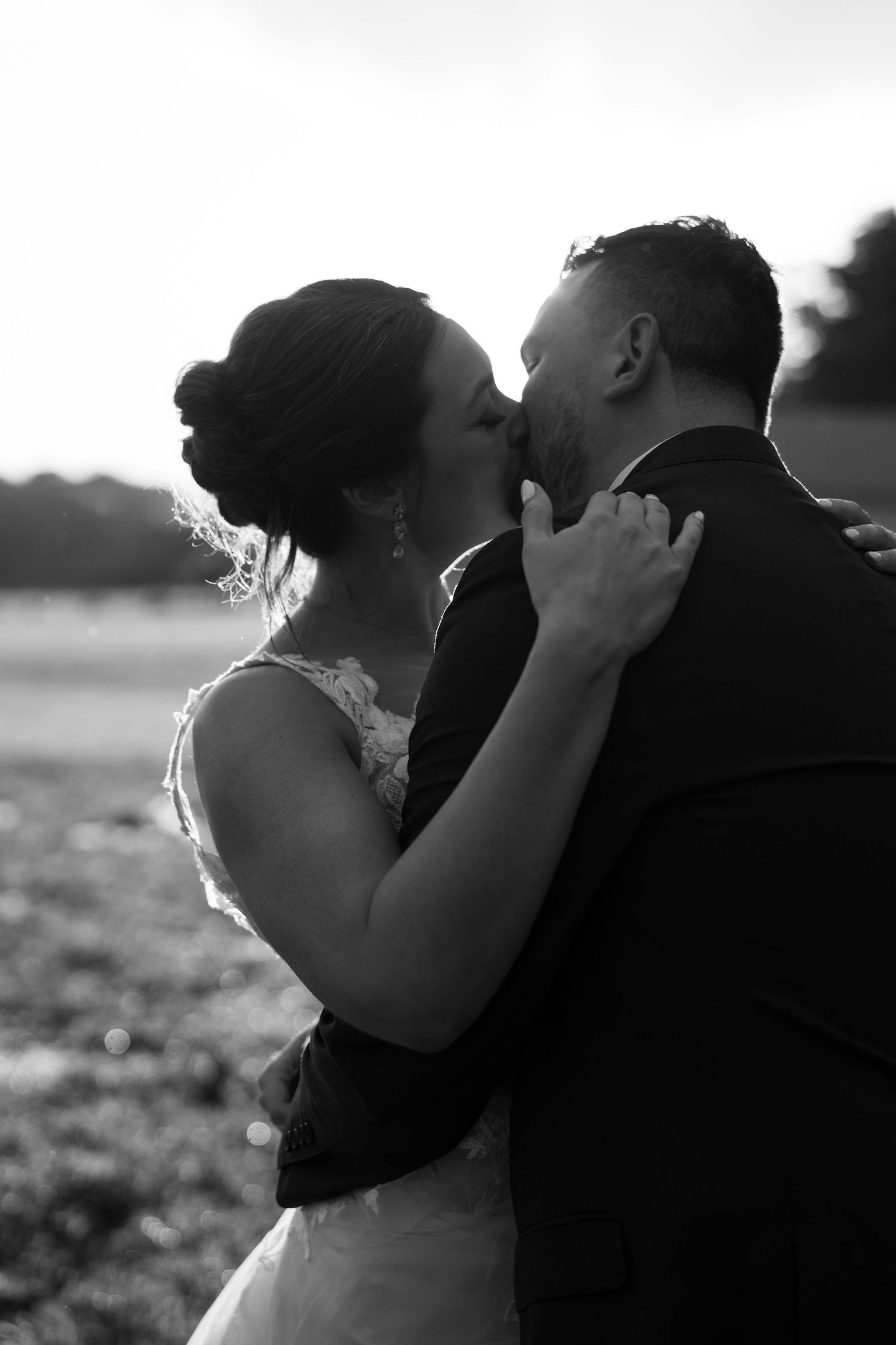 A romantic black and white photo sequence showing a couple sharing an intimate kiss in the sunlight.