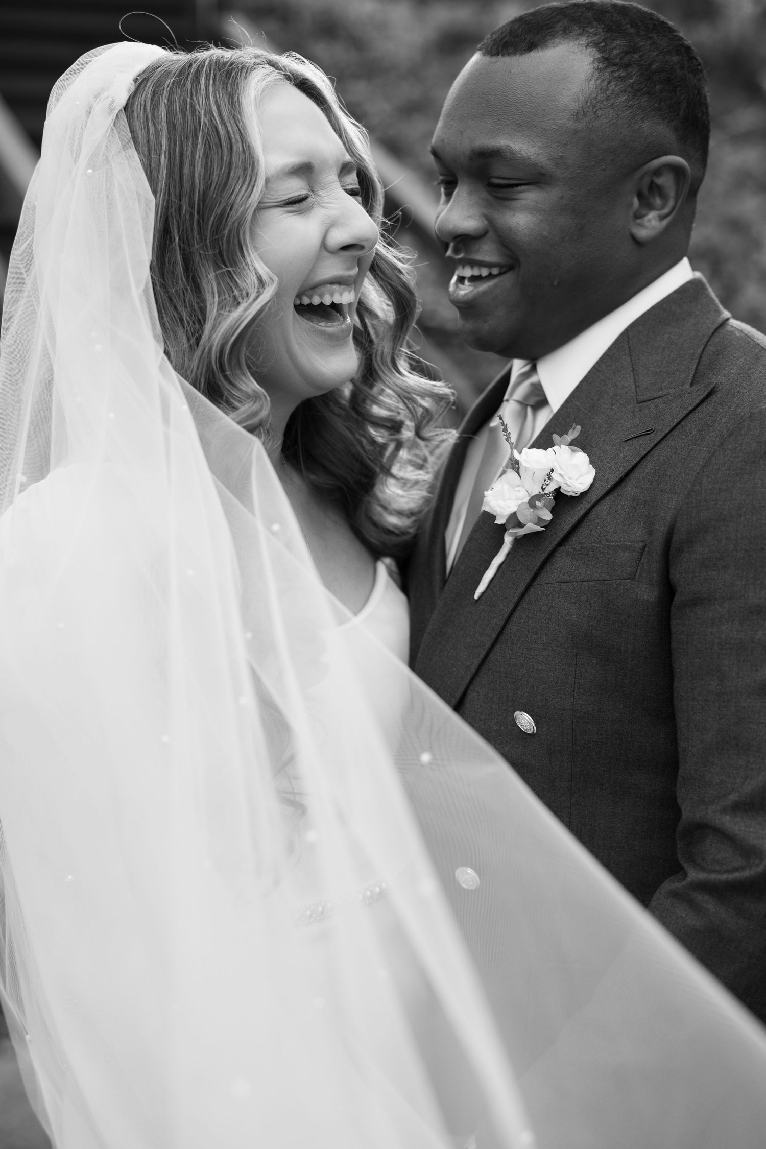 A happy newlywed couple shares joyful moments in black and white wedding portraits.