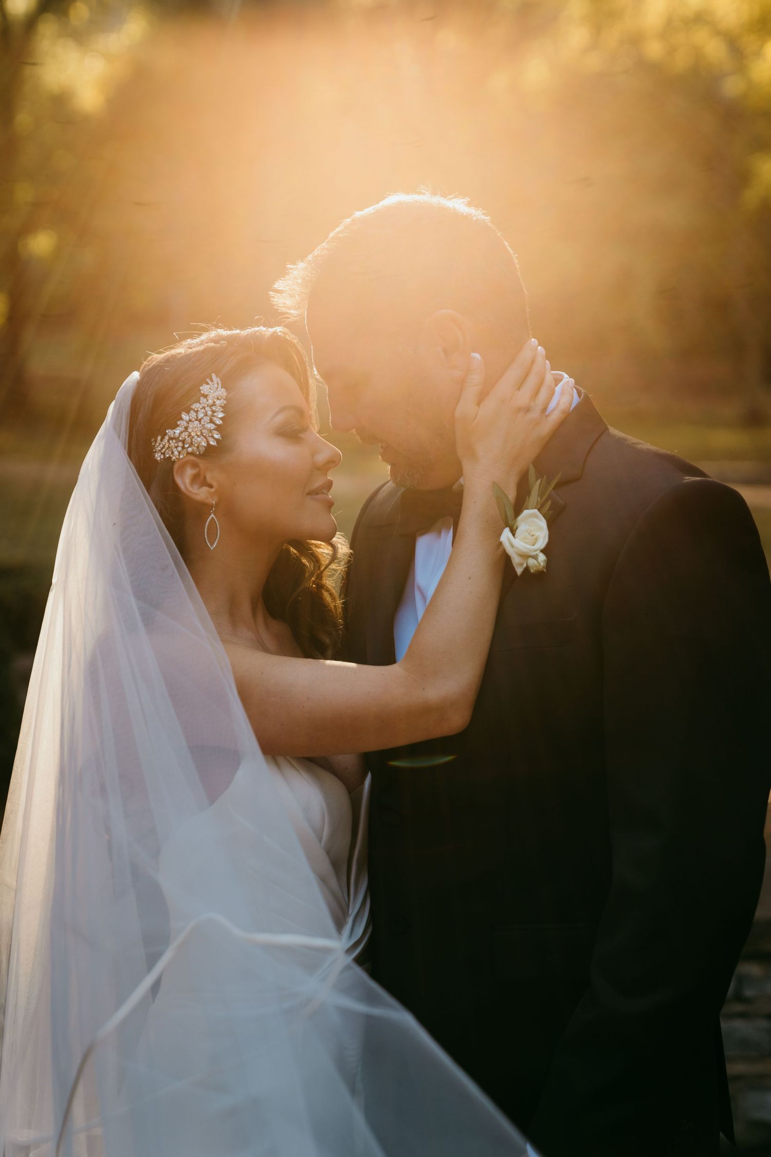 Romantic sunset wedding portrait with golden backlight and flowing veil.