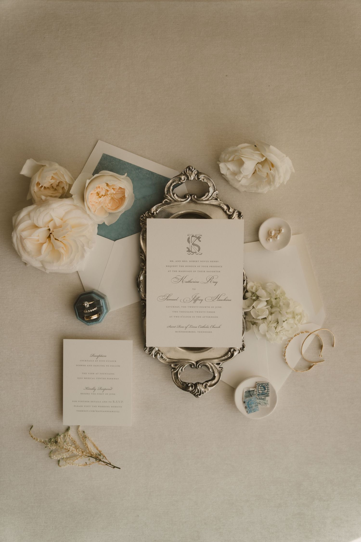 Wedding invitation suite with roses and vintage decor elements on beige background.