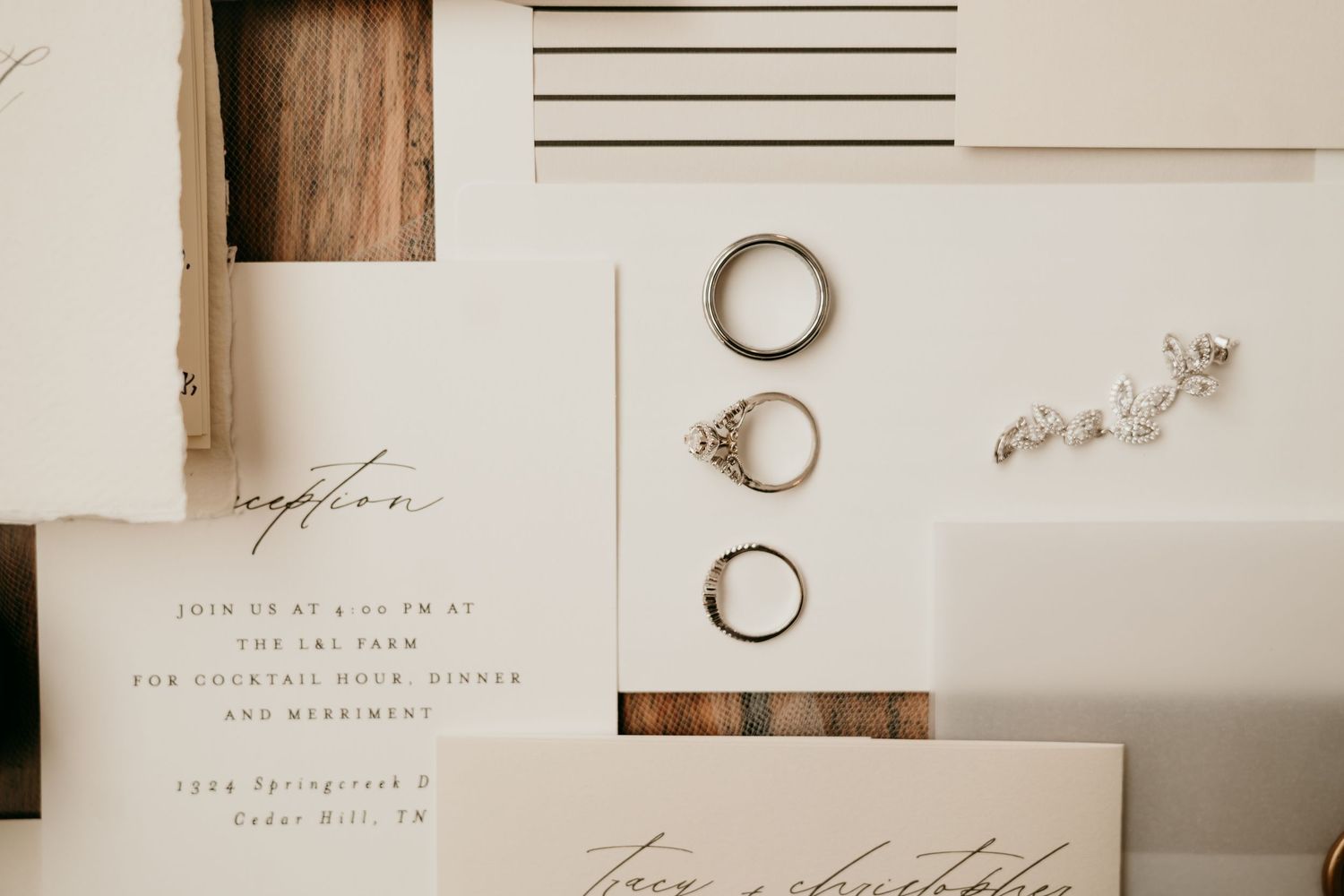 Minimalist wedding stationery and rings arranged on a white surface with natural lighting.