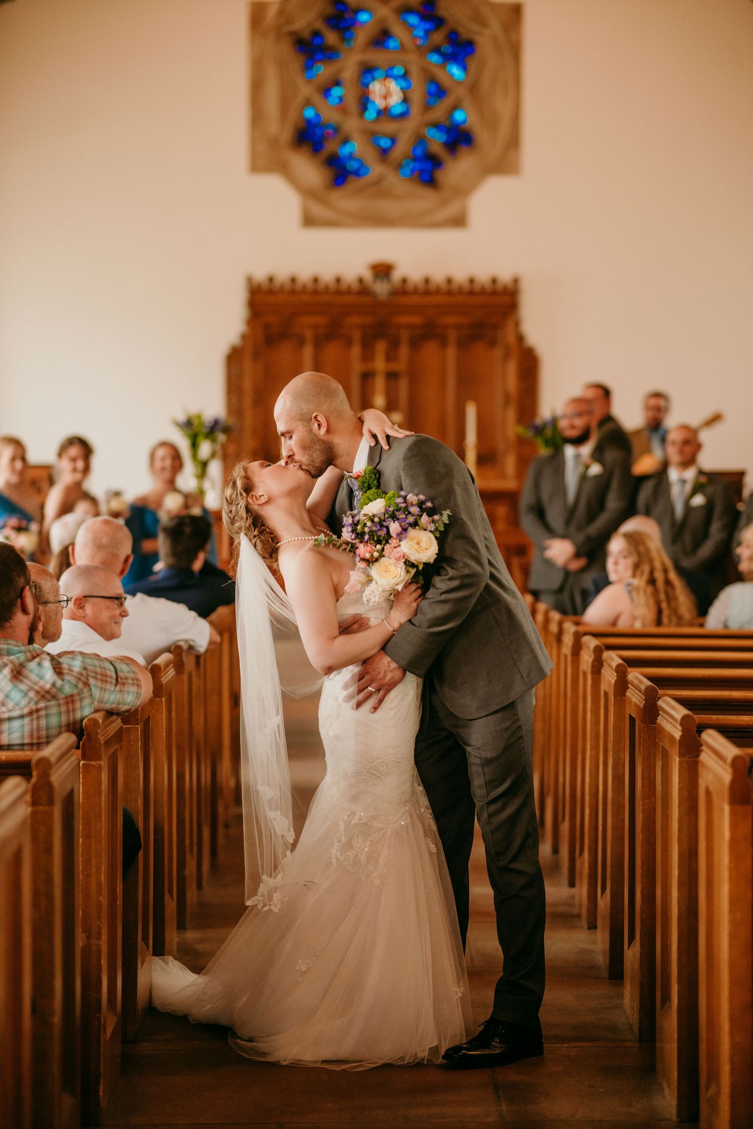 Wedding ceremony photos in a church with stained glass windows and wooden pews.