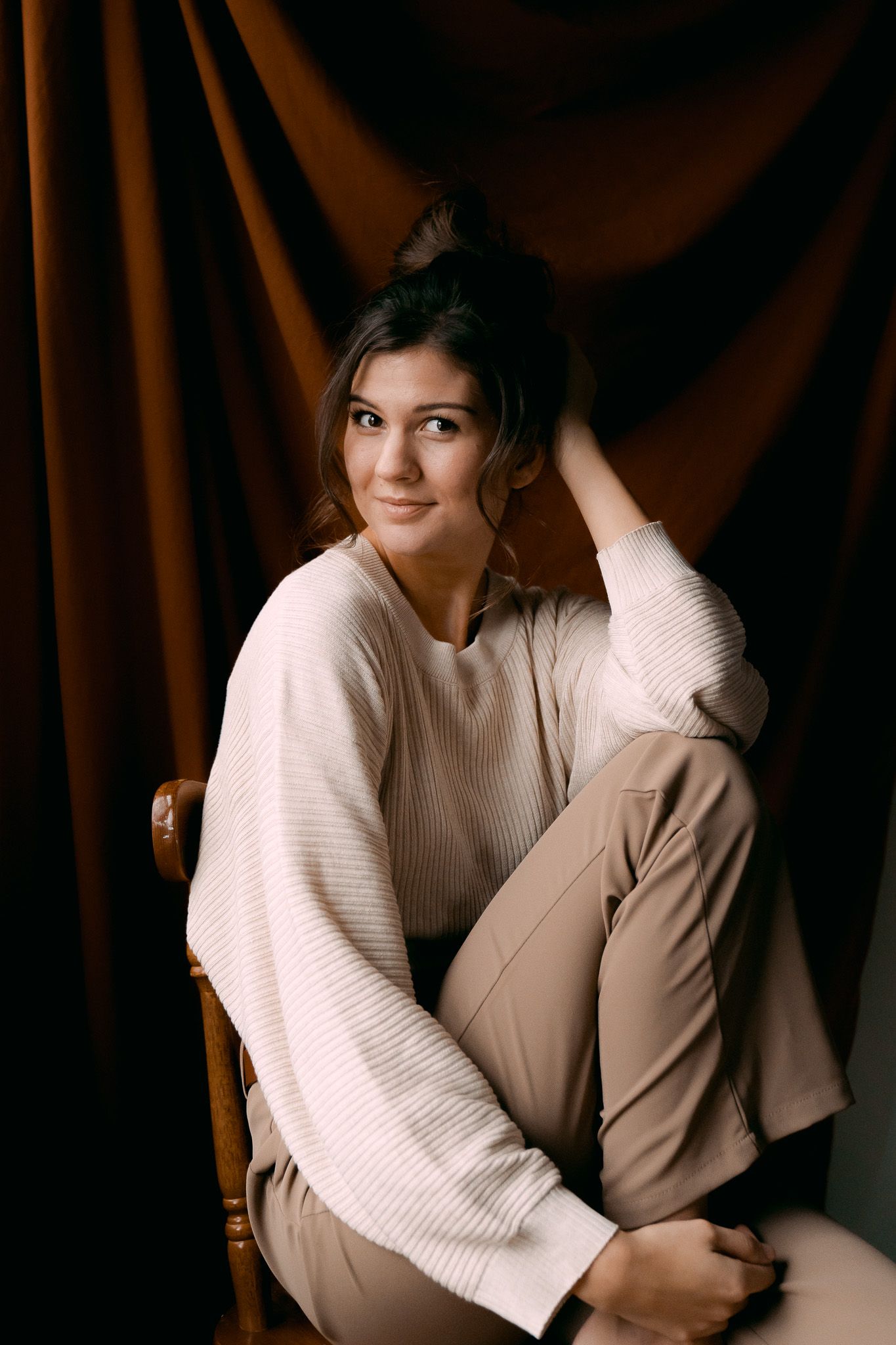 Casual portrait against brown velvet backdrop in cozy cream sweater.