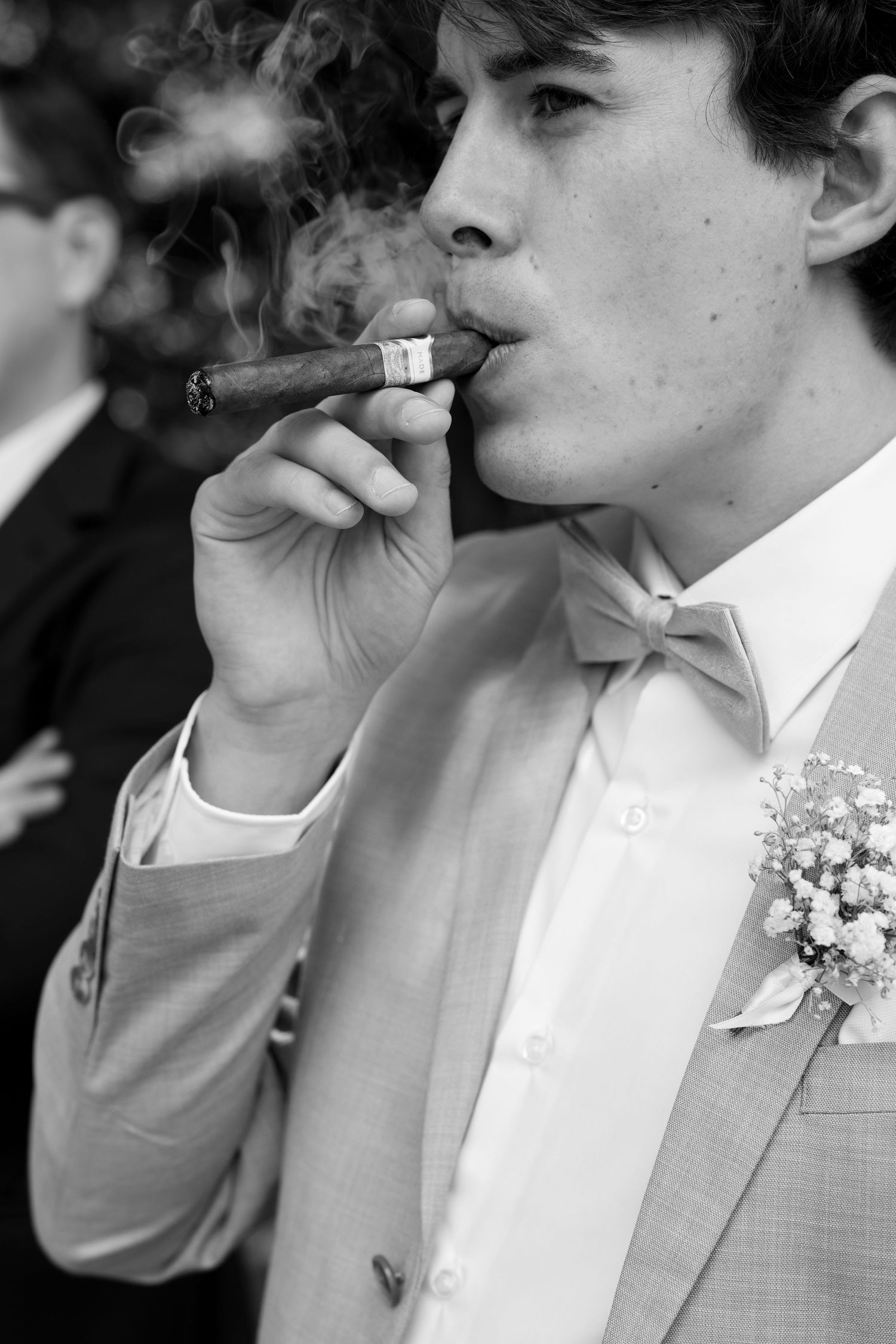 A black and white photo series of people in formal attire smoking cigars at a wedding celebration.