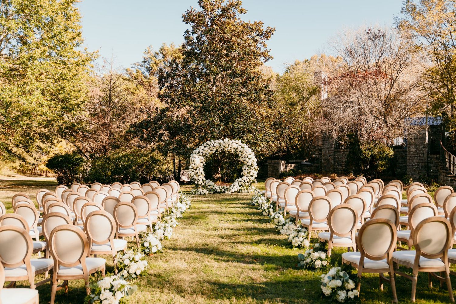 White chairs arranged for an outdoor autumn wedding ceremony with golden trees and sunlight filtering through the foliage in Nashville TN