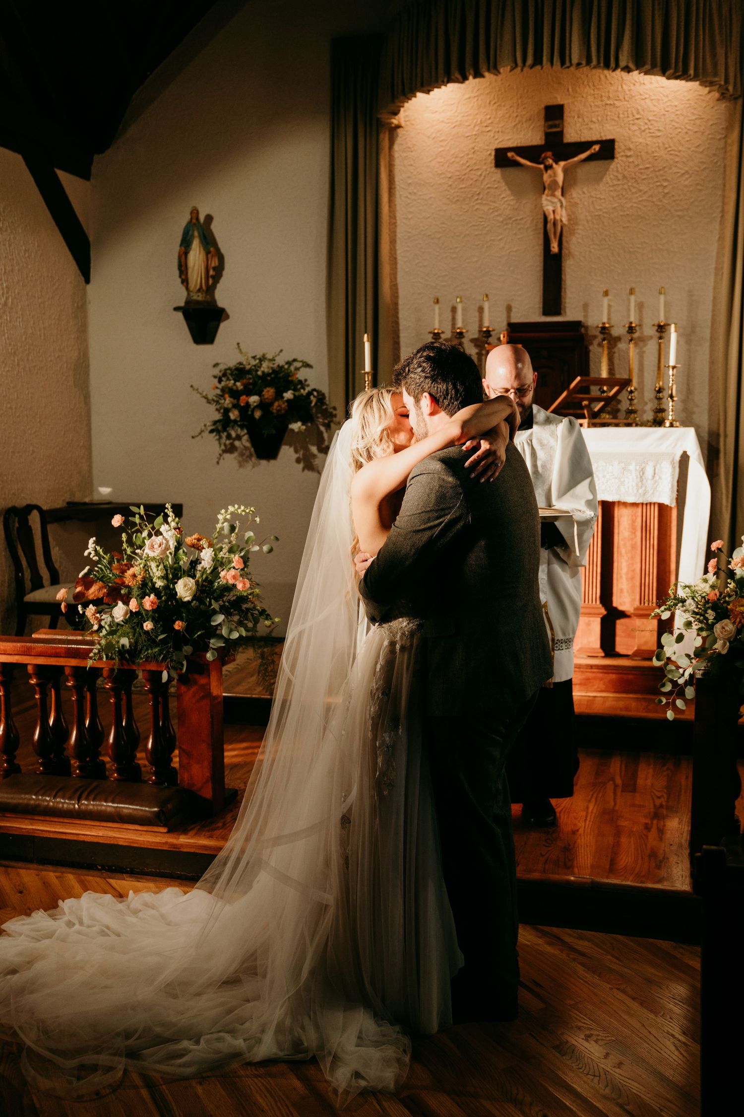 A wedding ceremony takes place in a traditional church sanctuary decorated with flowers.
