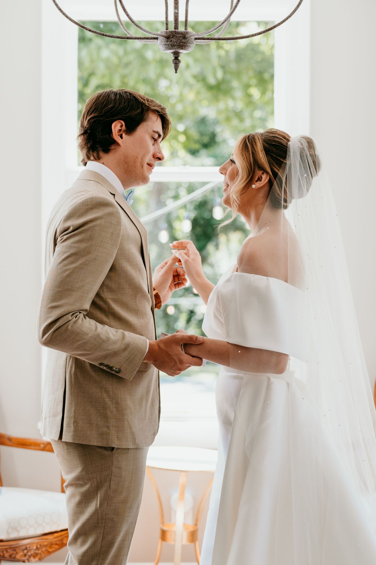 wedding couple shares a candid moment of laughter together in a sun-lit room with white walls elegant decor at Daras garden in Knoxville TN