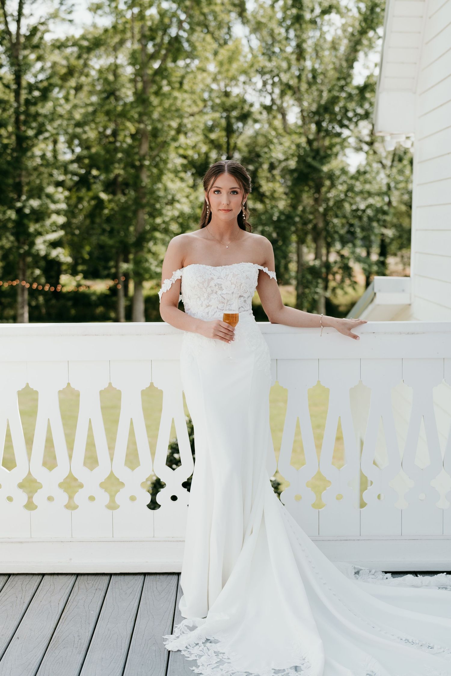 Wedding dress flowing over white porch railing on a sunny summer day.