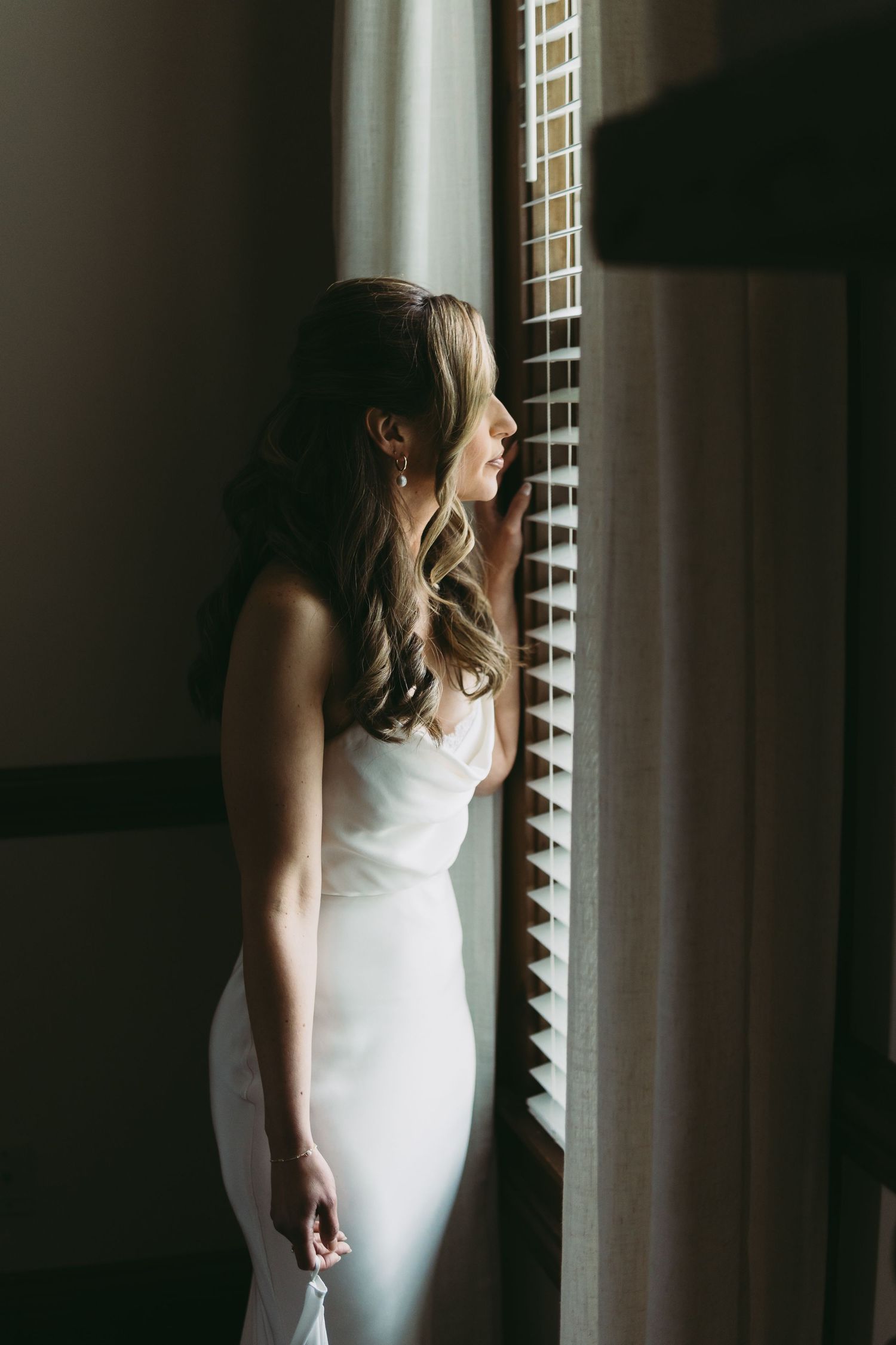 Dramatic window lighting creates silhouettes of a bride in her wedding gown.