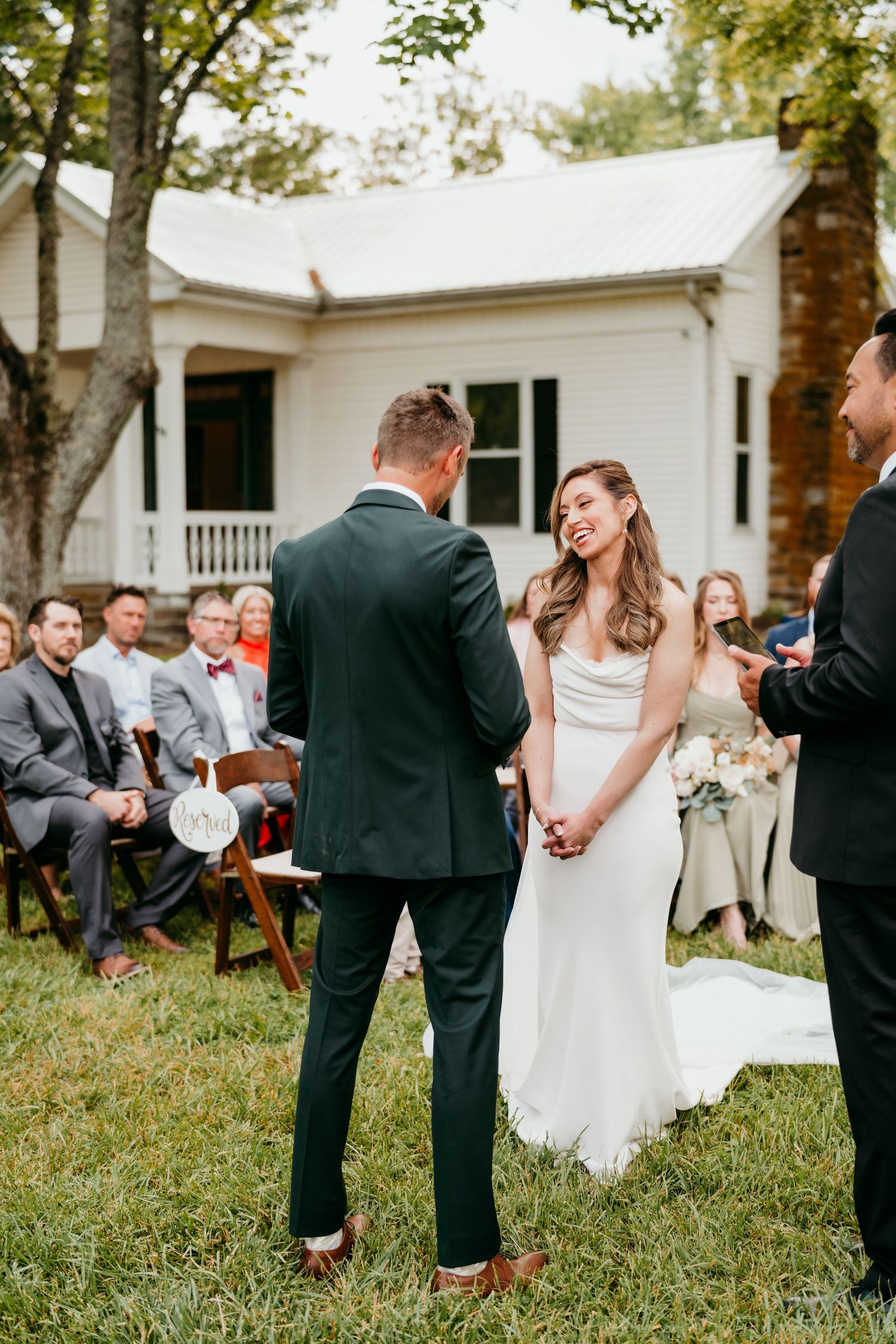 Intimate outdoor wedding ceremony in front of white farmhouse with seated guests at battle mountain farm in Nashville TN.