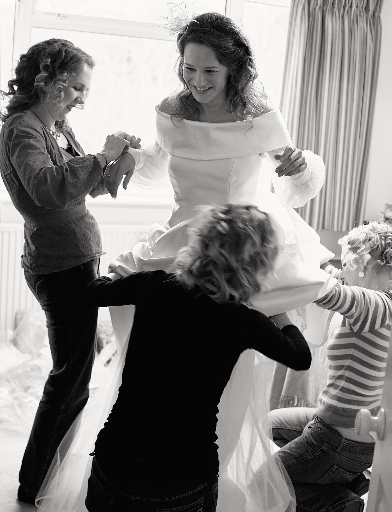Black and white photo showing preparations of a bride in her wedding dress.