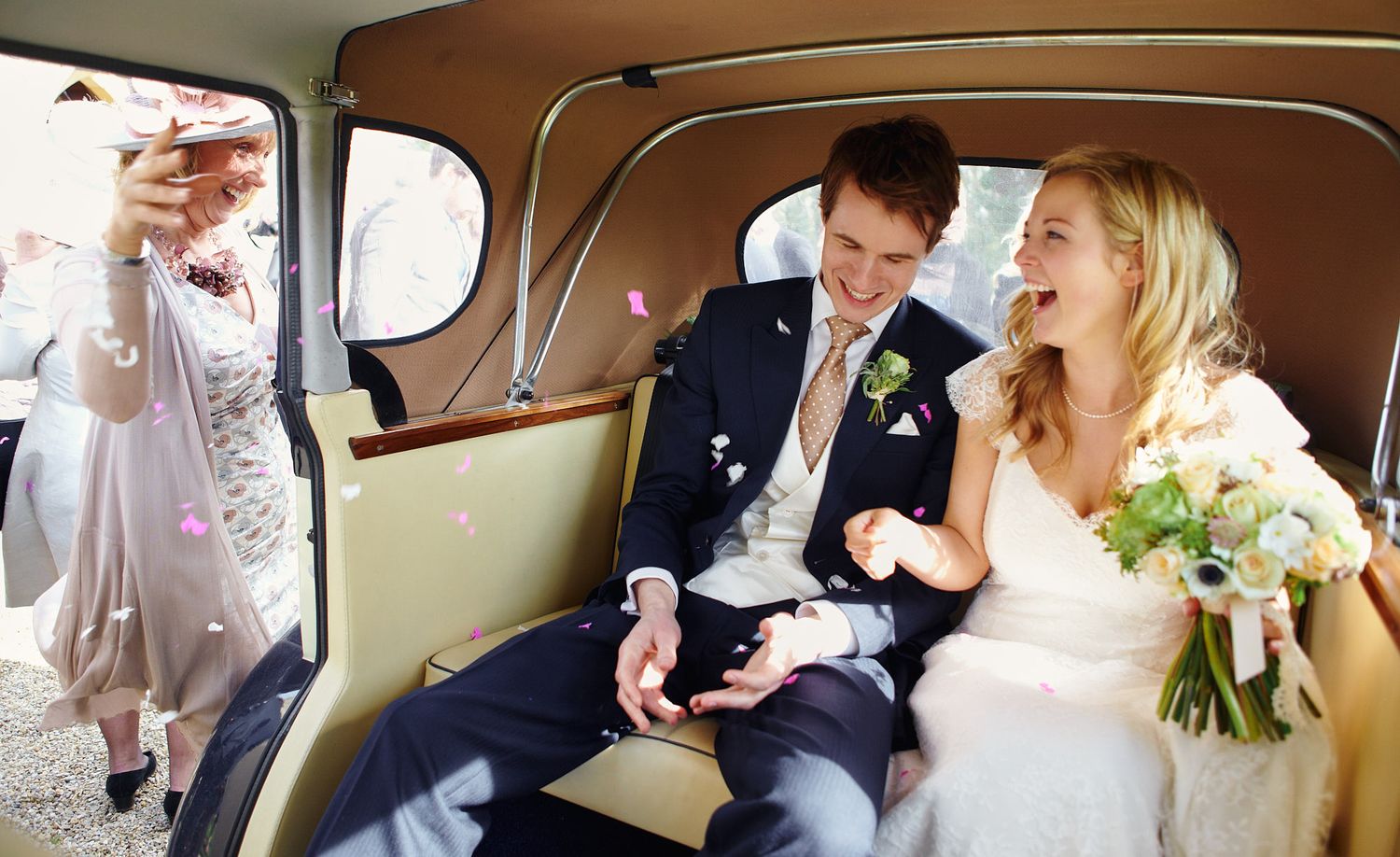 Wedding party riding in a classic vintage car interior sharing happy moments together.