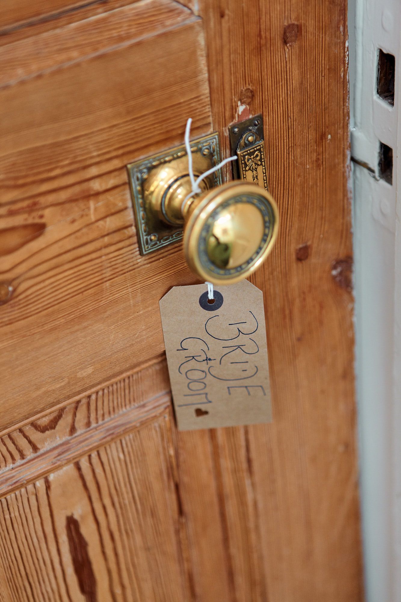 Close-up of vintage brass doorknob with rustic wooden door detail at wedding in Brighton, Sussex.