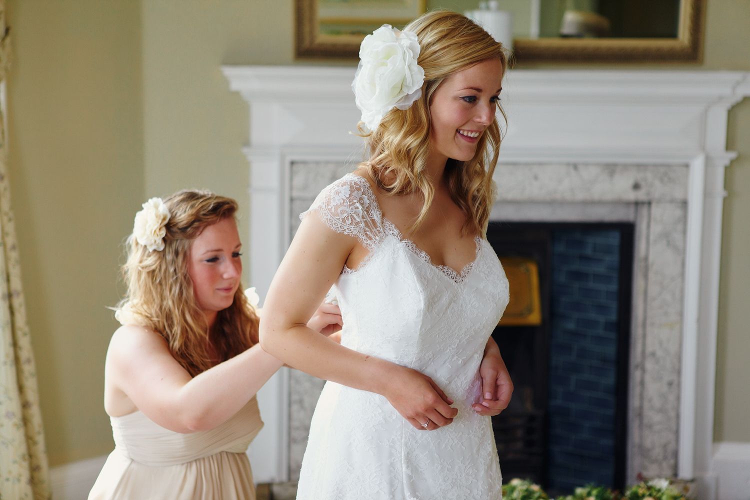 Bridal party helping with wedding preparations in an elegant room with fireplace.