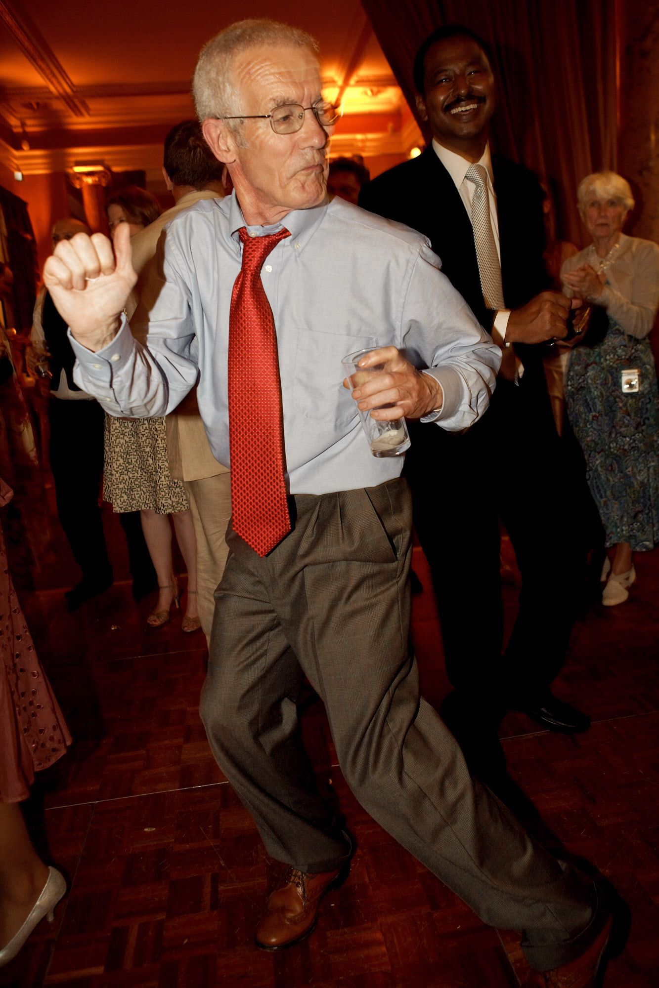 Energetic wedding guest dancing enthusiastically at reception in formal attire.