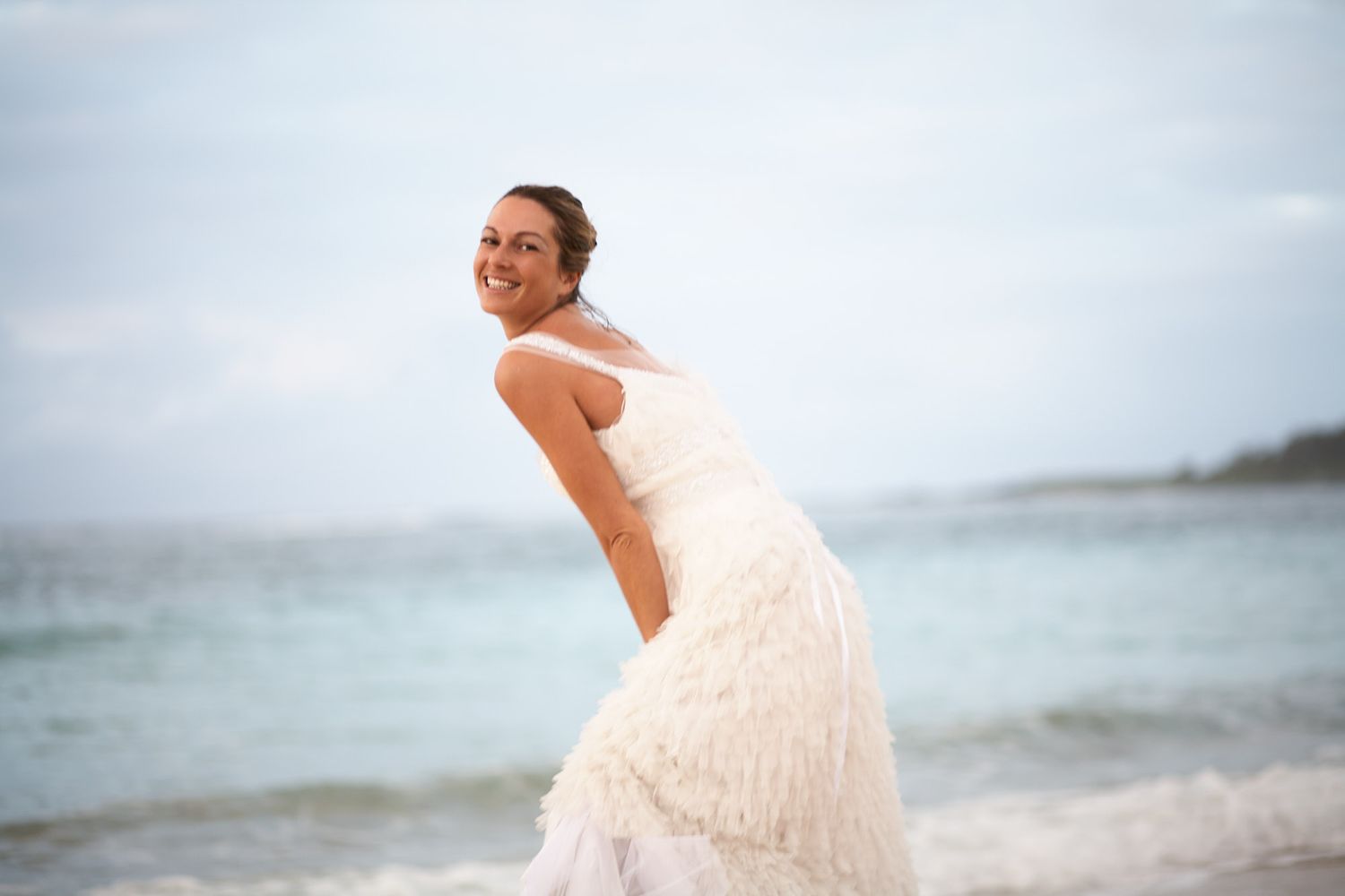 Bride twirls in flowing white dress along oceanfront setting in Mauritius on destination wedding.