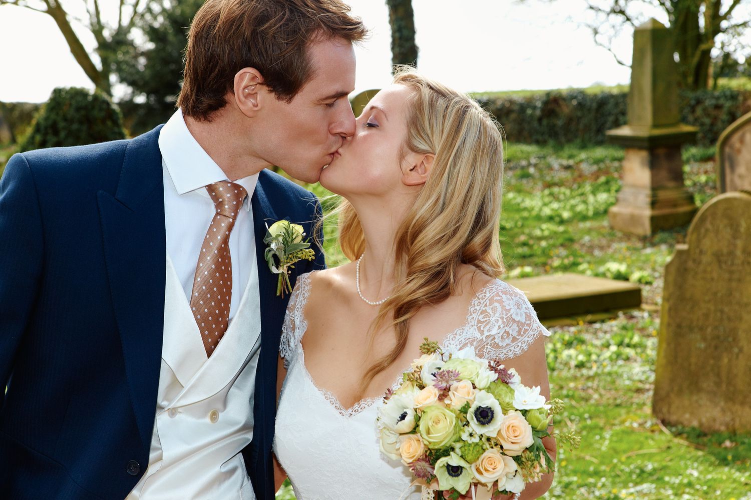 Wedding couple sharing romantic kiss in outdoor garden setting.