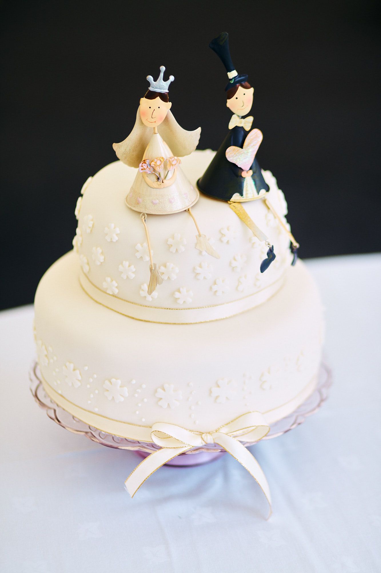 White wedding cake decorated with delicate crowns and intricate details on a table.